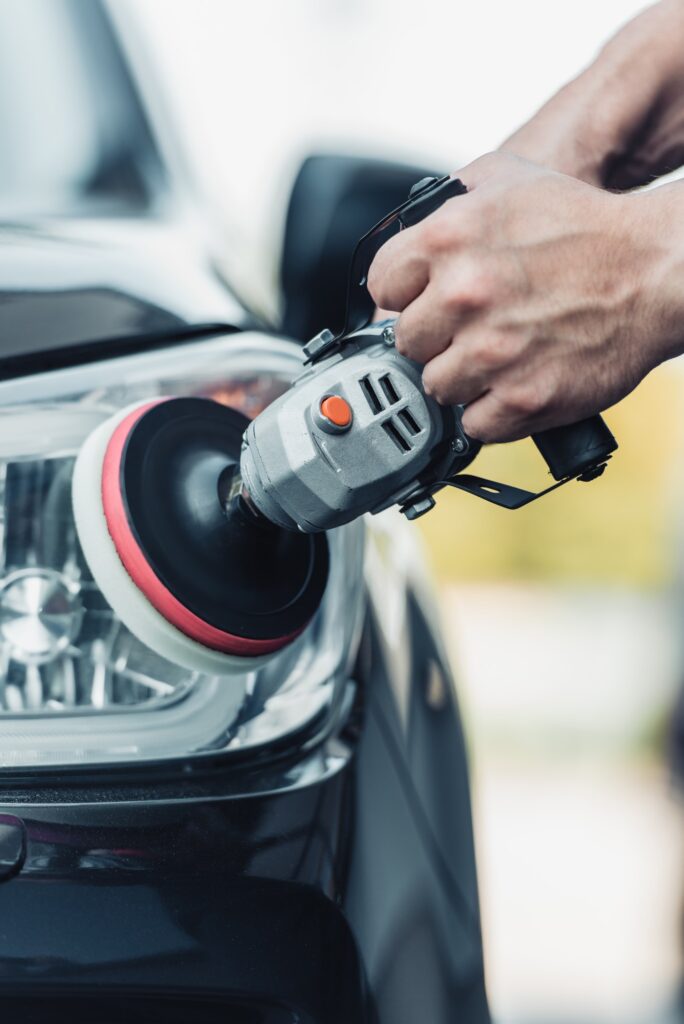 cropped view of car cleaner polishing rear lamp with polish machine